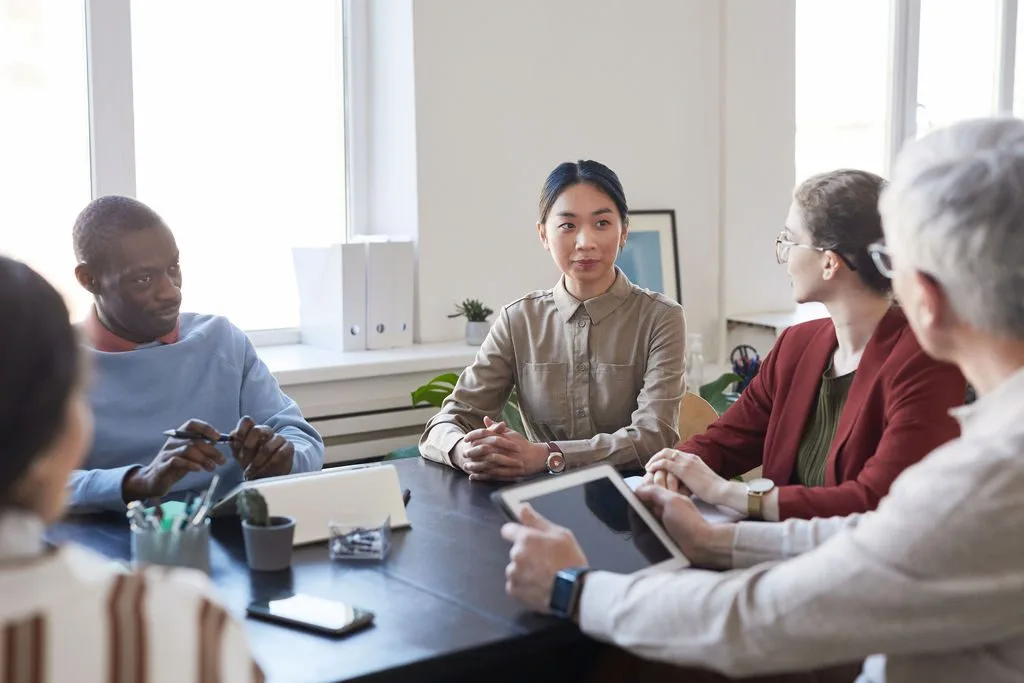 A planning conversation at a table with laptops and documents