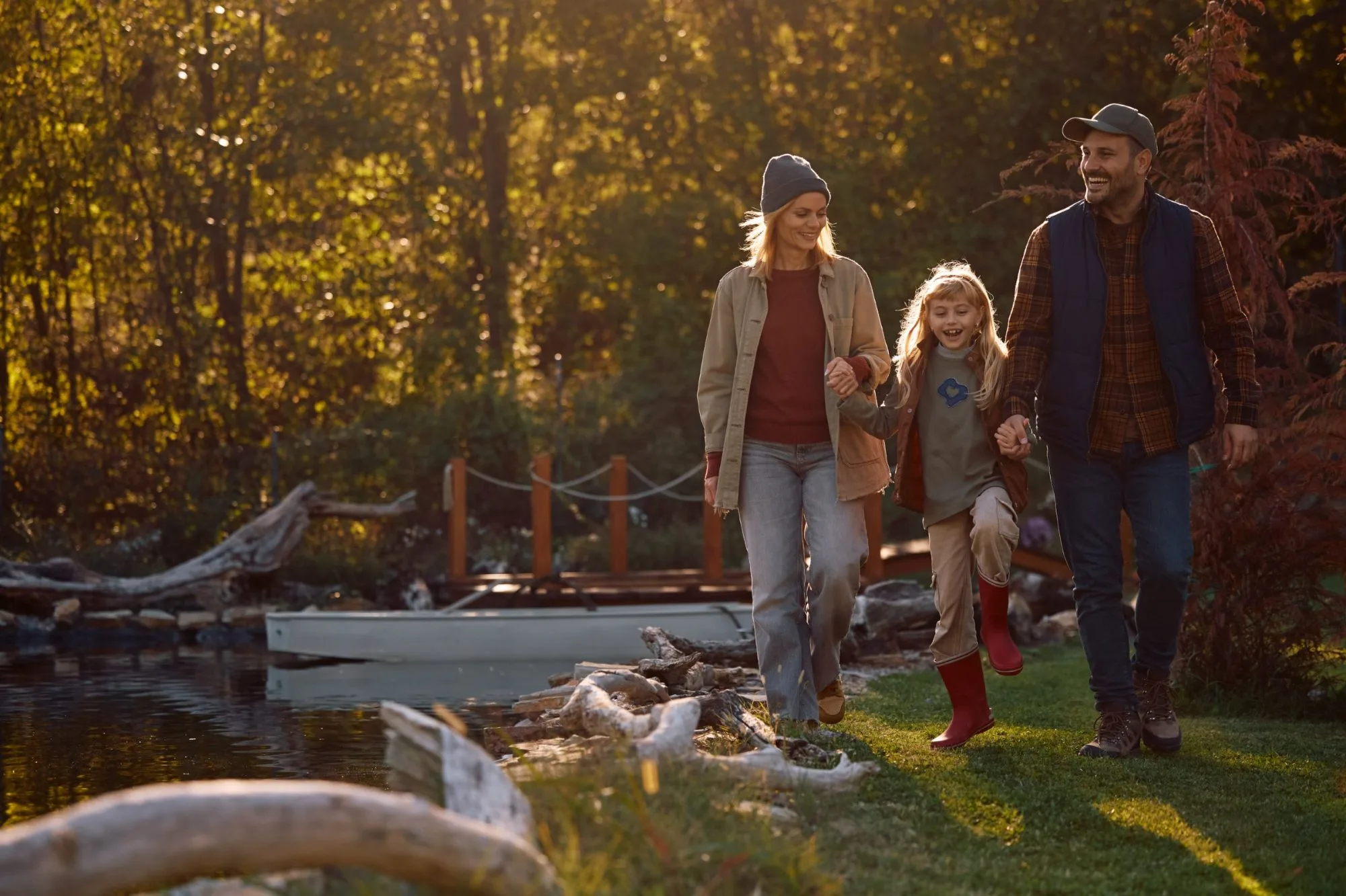 A family walking a lakeside path in late afternoon light