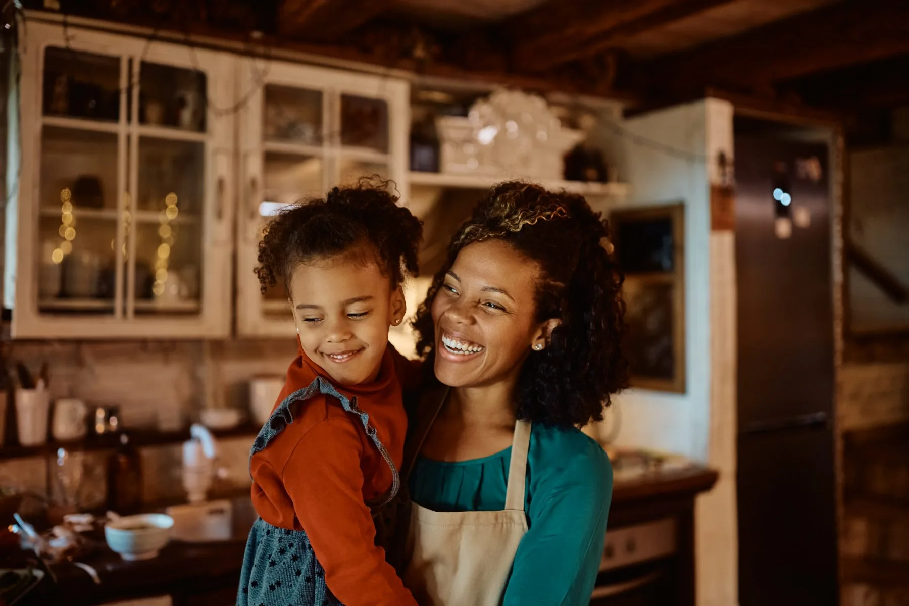 A mother and daughter laughing together in their kitchen