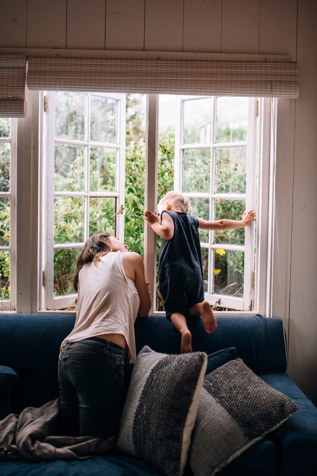 A mother and toddler at a sunlit window