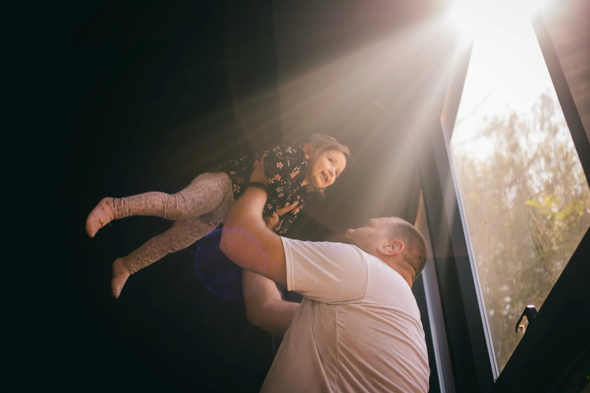A father lifting his daughter into the afternoon light
